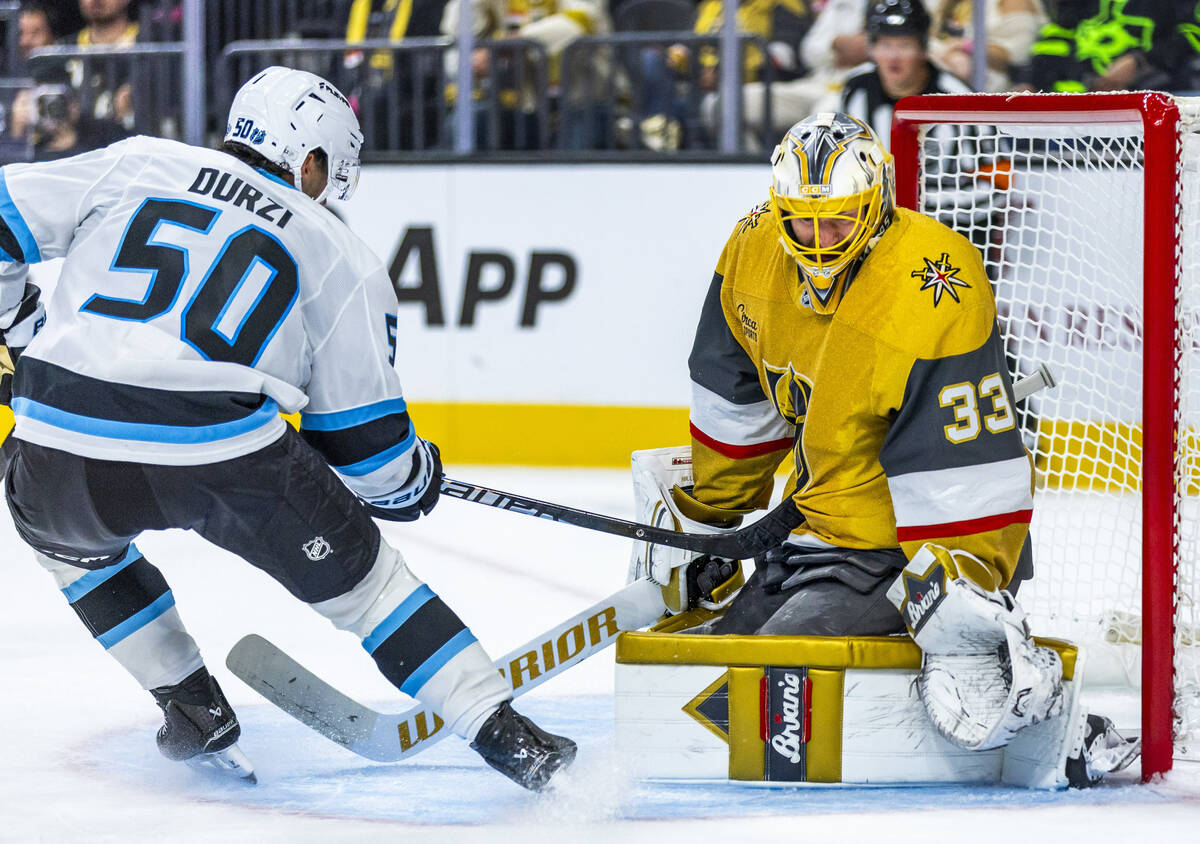 Utah Mammoth defenseman Sean Durzi (50) drives his stick into Golden Knights goaltender Adin Hi ...