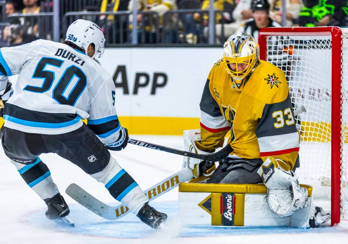Utah Mammoth defenseman Sean Durzi (50) drives his stick into Golden Knights goaltender Adin Hi ...