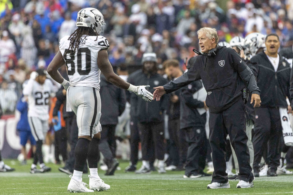 Raiders head coach Pete Carroll welcomes Raiders tight end Ian Thomas (80) back to the sideline ...