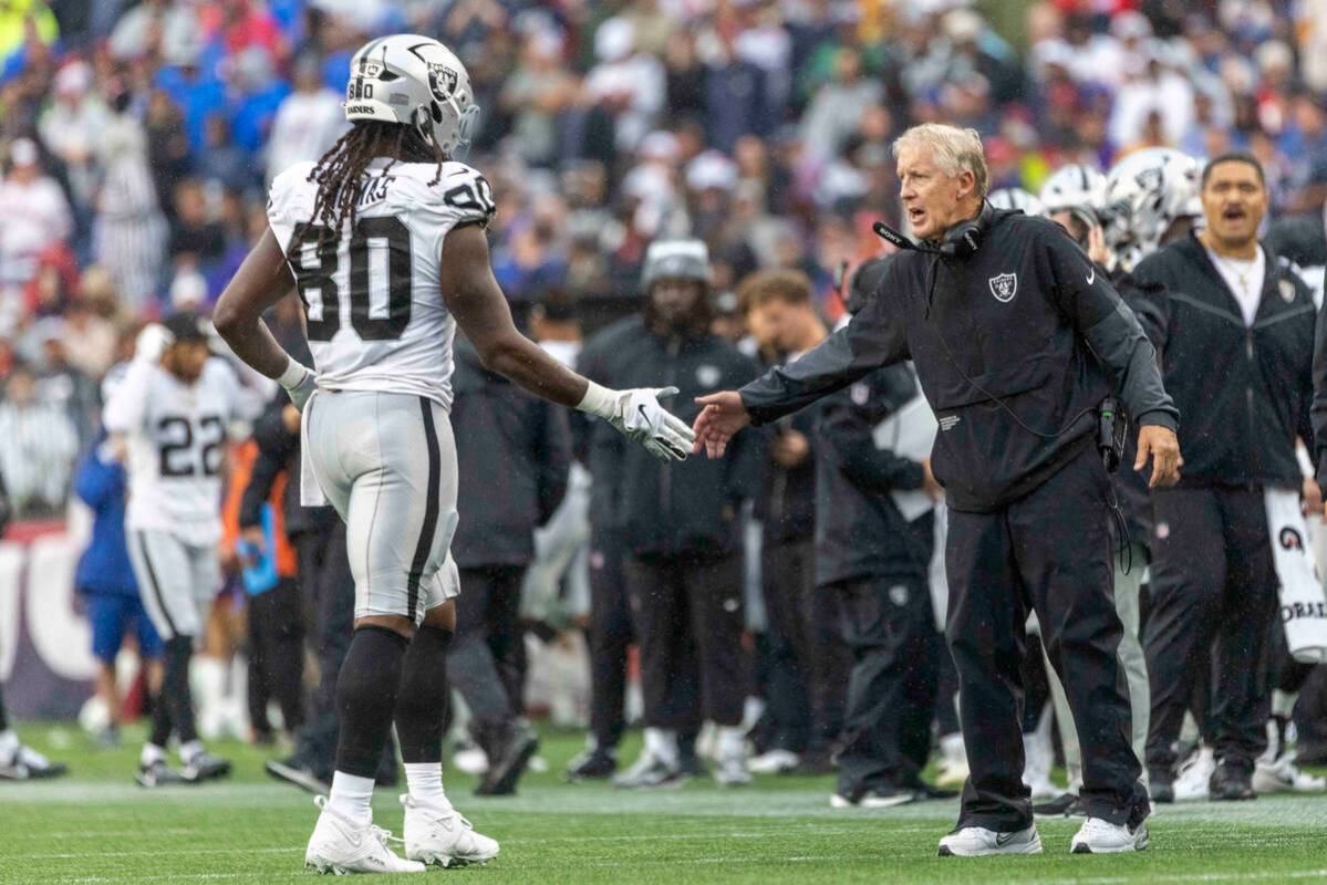 Raiders head coach Pete Carroll welcomes Raiders tight end Ian Thomas (80) back to the sideline ...