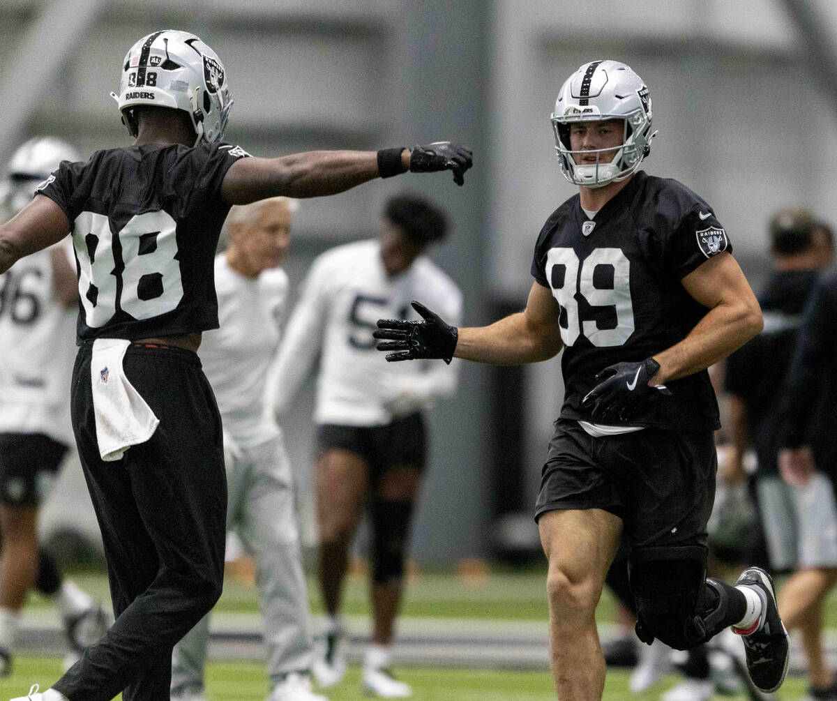 Raiders tight end Brock Bowers (89) runs to greet tight end Justin Shorter (88) during the team ...