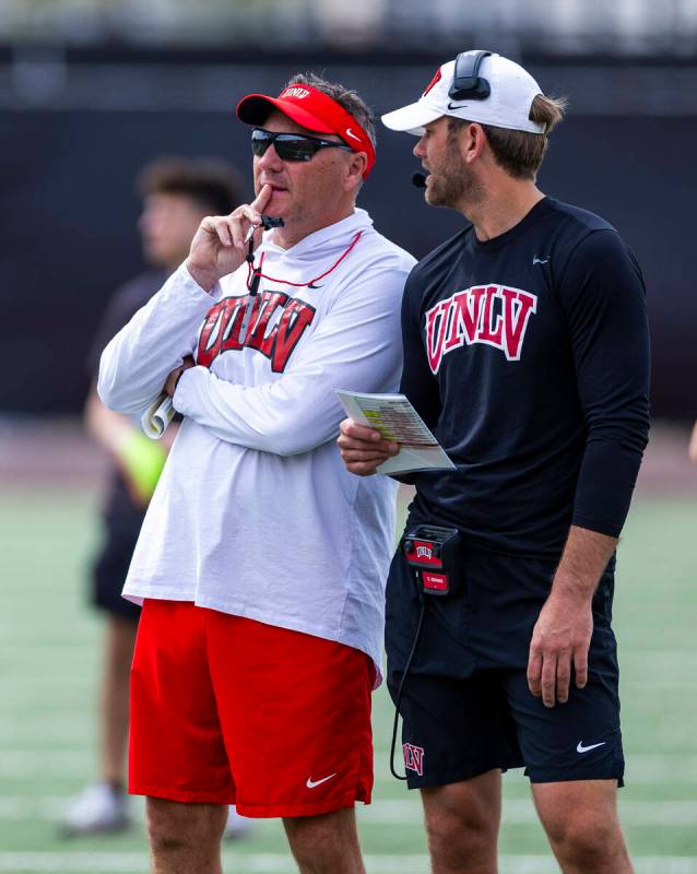 UNLV head coach Dan Mullen talks with offensive coordinator/quarterbacks coach Corey Dennis dur ...