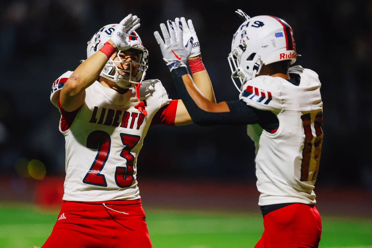 Liberty teammates Blain Kupahu (19) and Rysen Dacosin-Arcala high-five during a high school foo ...