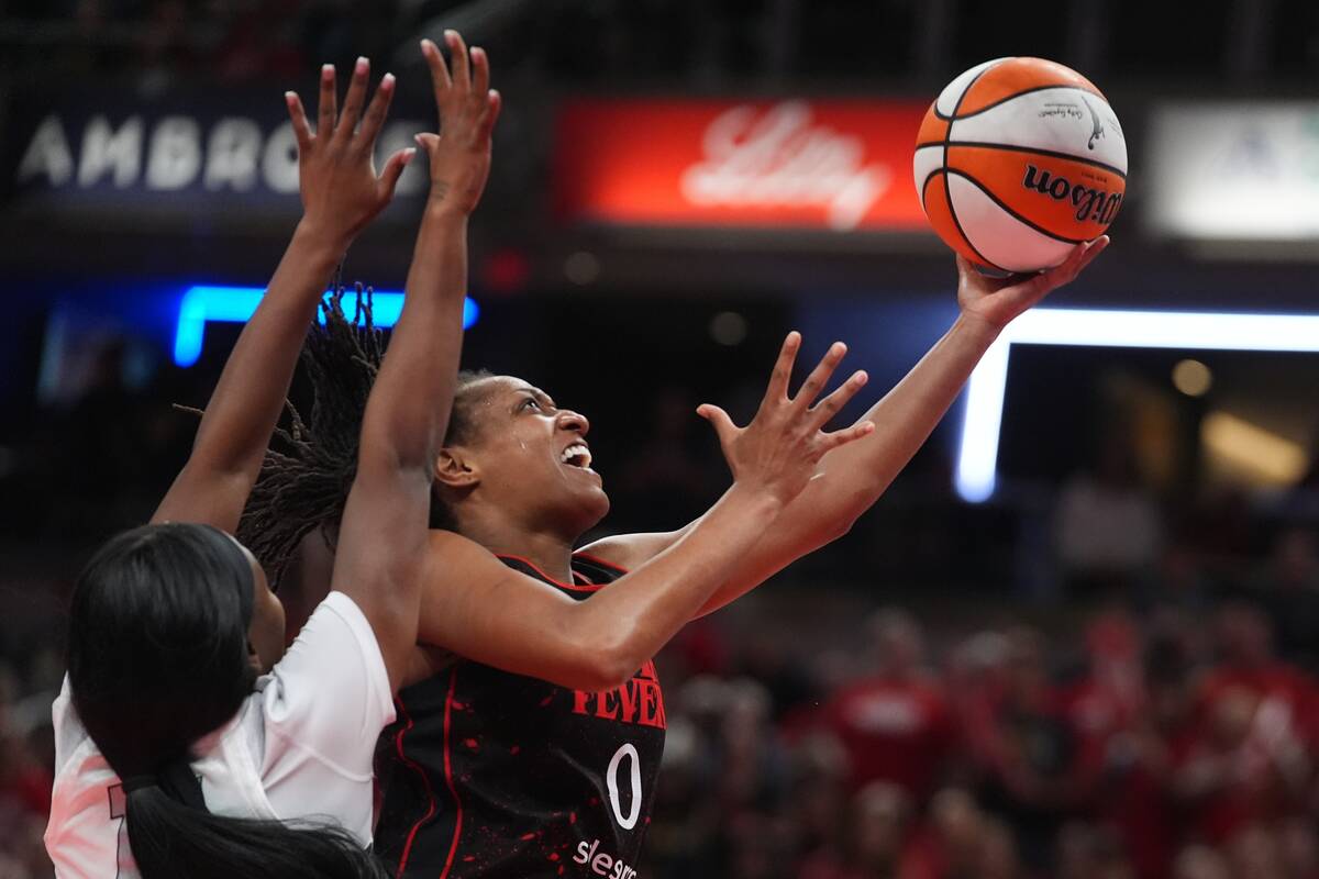 Indiana Fever's Kelsey Mitchell (0) puts up a shot against Las Vegas Aces' Dana Evans ...