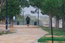 A person goes for cover as a storm sets in above Sunset Park Friday, Sept. 26, 2025, in Henders ...