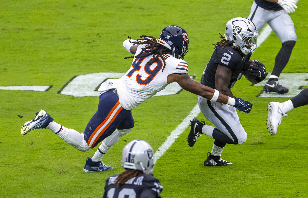 Raiders running back Ashton Jeanty (2) blast through the line pursued pursued by Chicago Bears ...