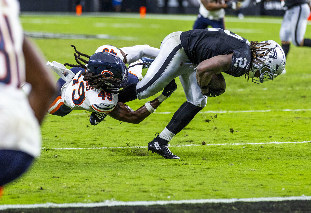 Raiders running back Ashton Jeanty (2) works to break a tackle attempt by Chicago Bears middle ...