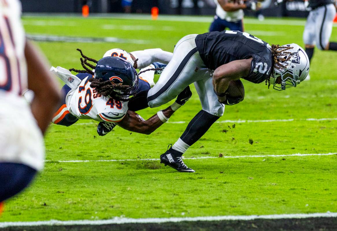 Raiders running back Ashton Jeanty (2) works to break a tackle attempt by Chicago Bears middle ...