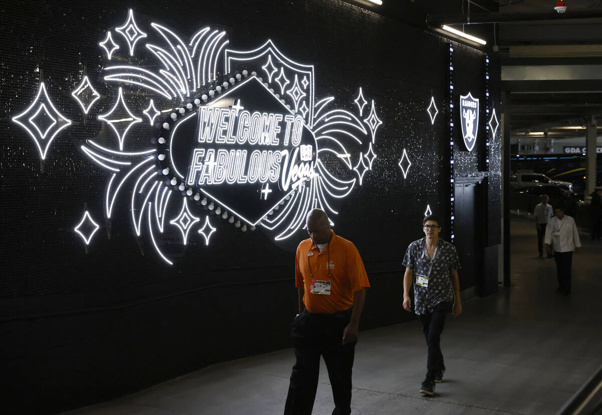 Workers walk throug the "Welcome to Fabulous Las Vegas" walk during an NFL football g ...