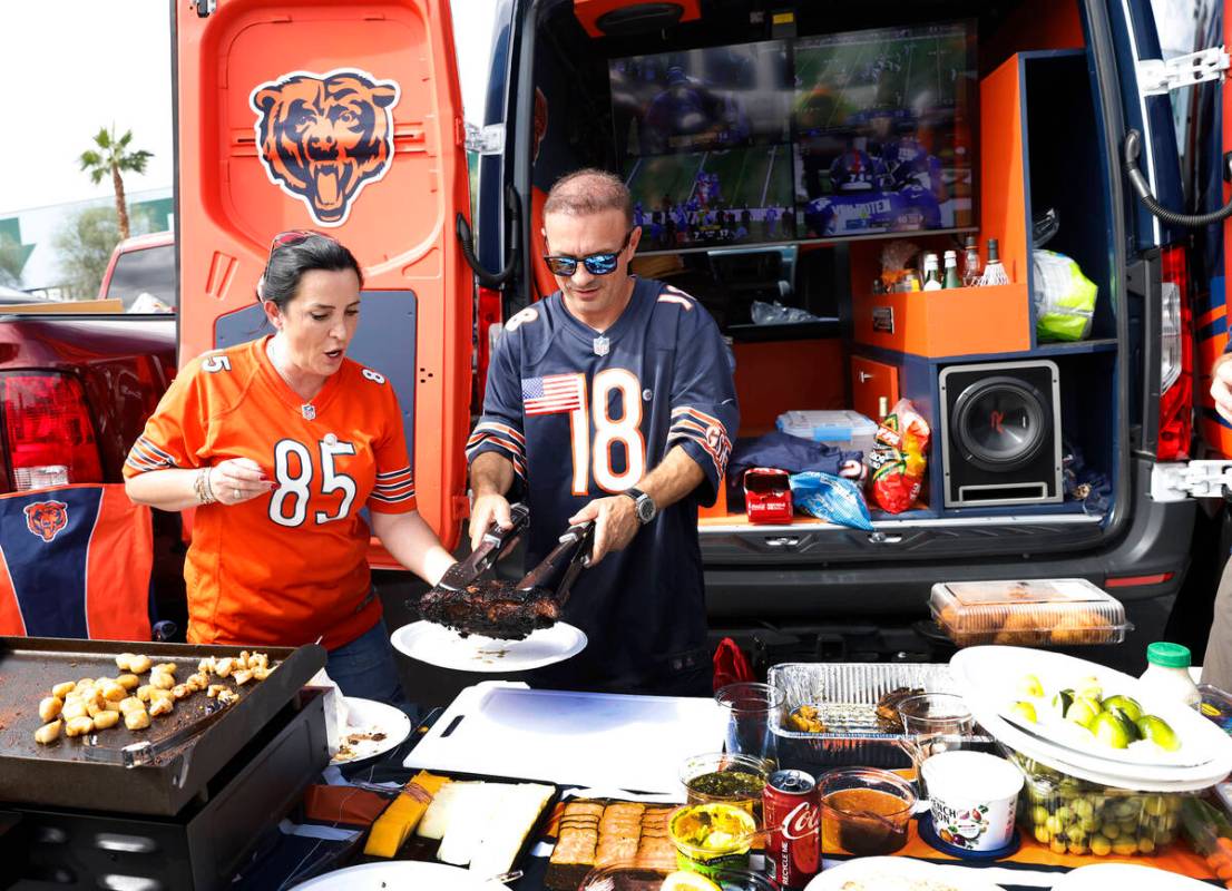 Chicago Bears fans Ridvan Aika, left, and Alex Idriz, both of Chicago, prepare food as they tai ...