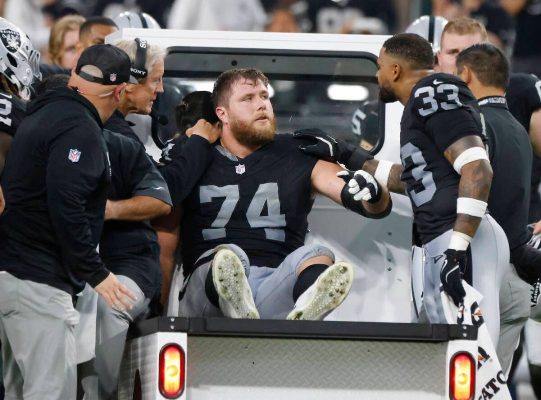 Raiders offensive tackle Kolton Miller (74) is comforted by head coach Pete Carroll, left, and ...