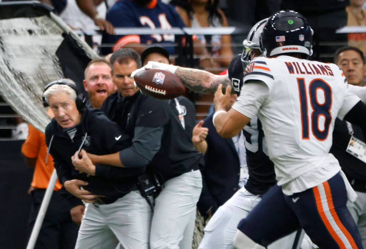 Raiders head coach Pete Carrol, left, watches as defensive end Maxx Crosby (98) runs with the b ...