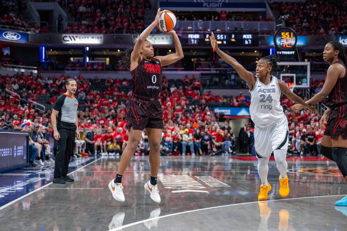 Indiana Fever guard Kelsey Mitchell (0) goes up to shoot while defended by Las Vegas Aces guard ...