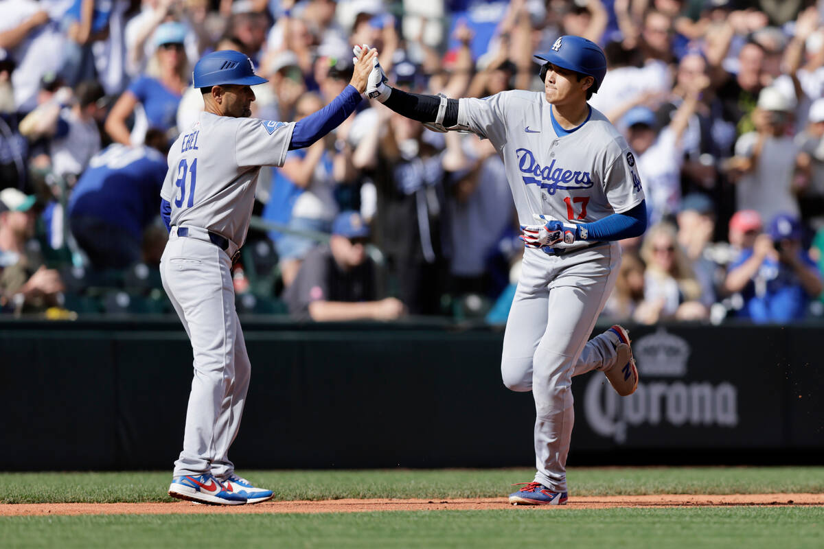 Los Angeles Dodgers third base coach Dino Ebel greets Shohei Ohtani as he runs the bases on his ...