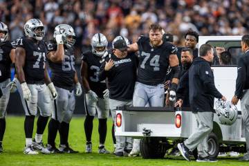 Raiders offensive tackle Kolton Miller (74) is assisted off the field as teammates gather aroun ...