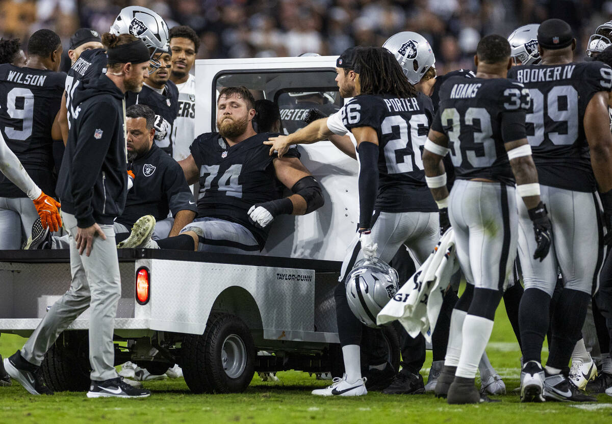 Raiders offensive tackle Kolton Miller (74) is assisted off the field as teammates gather aroun ...