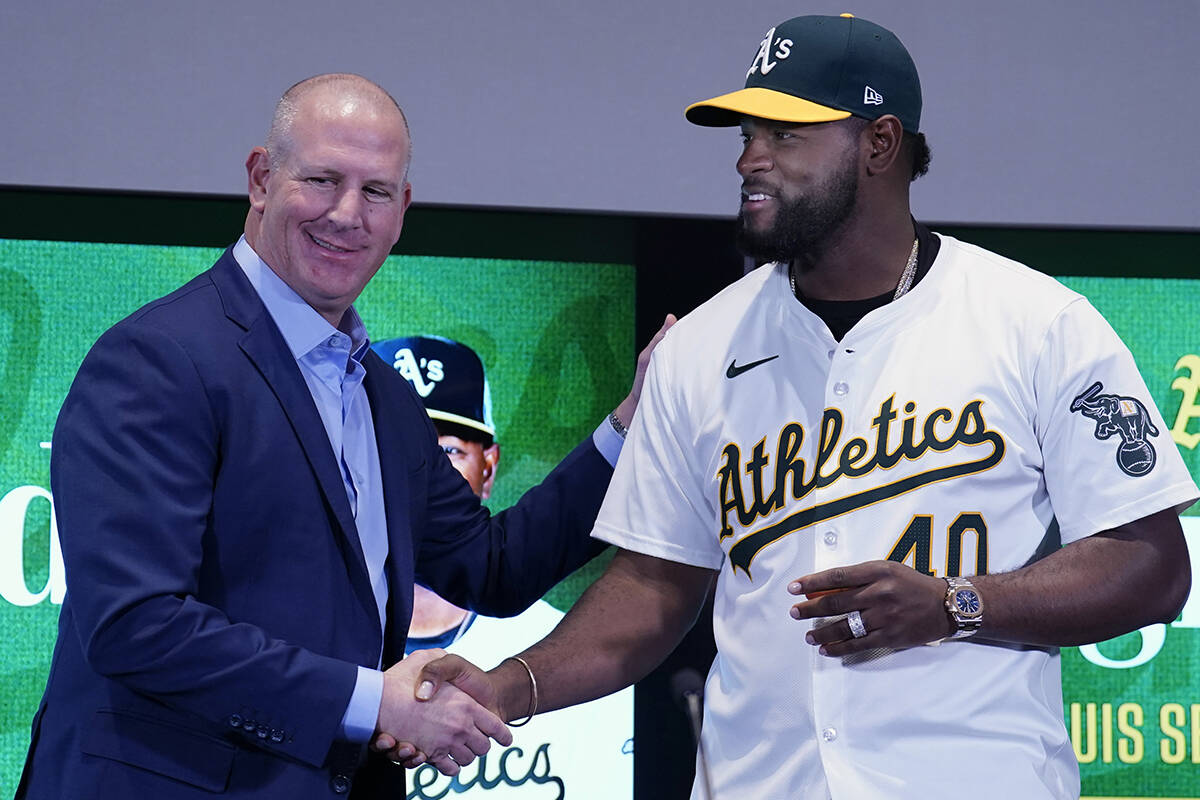 Athletics baseball team General Manager David Forst, left, shakes hands with pitcher Luis Sever ...