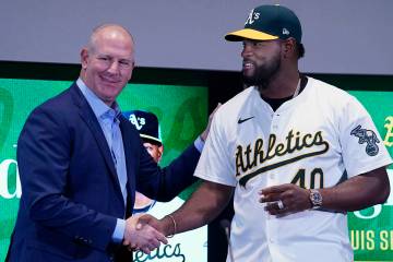 Athletics baseball team General Manager David Forst, left, shakes hands with pitcher Luis Sever ...