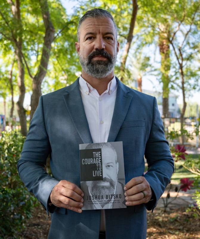 Former Metro police officer Joshua Bitsko holds his newly authored book while standing for a po ...