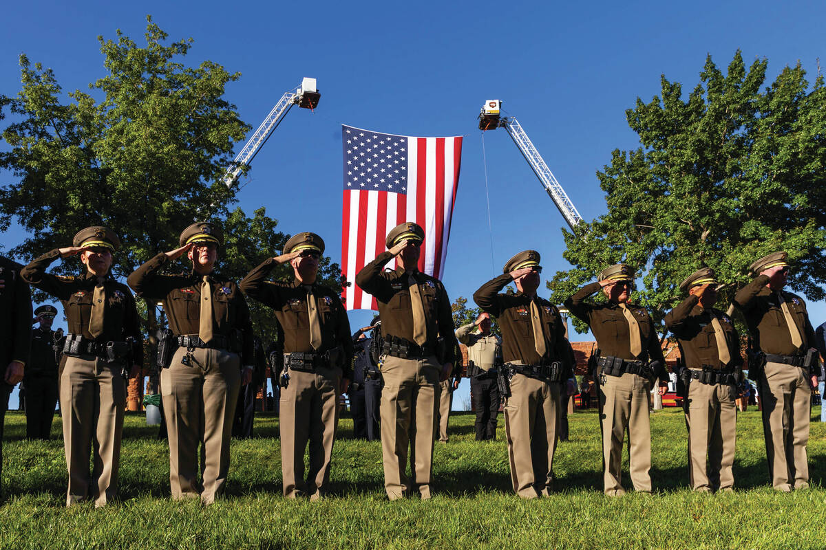 Police and firefighters salute as "Taps" is played by the Southern Nevada Multiagency ...