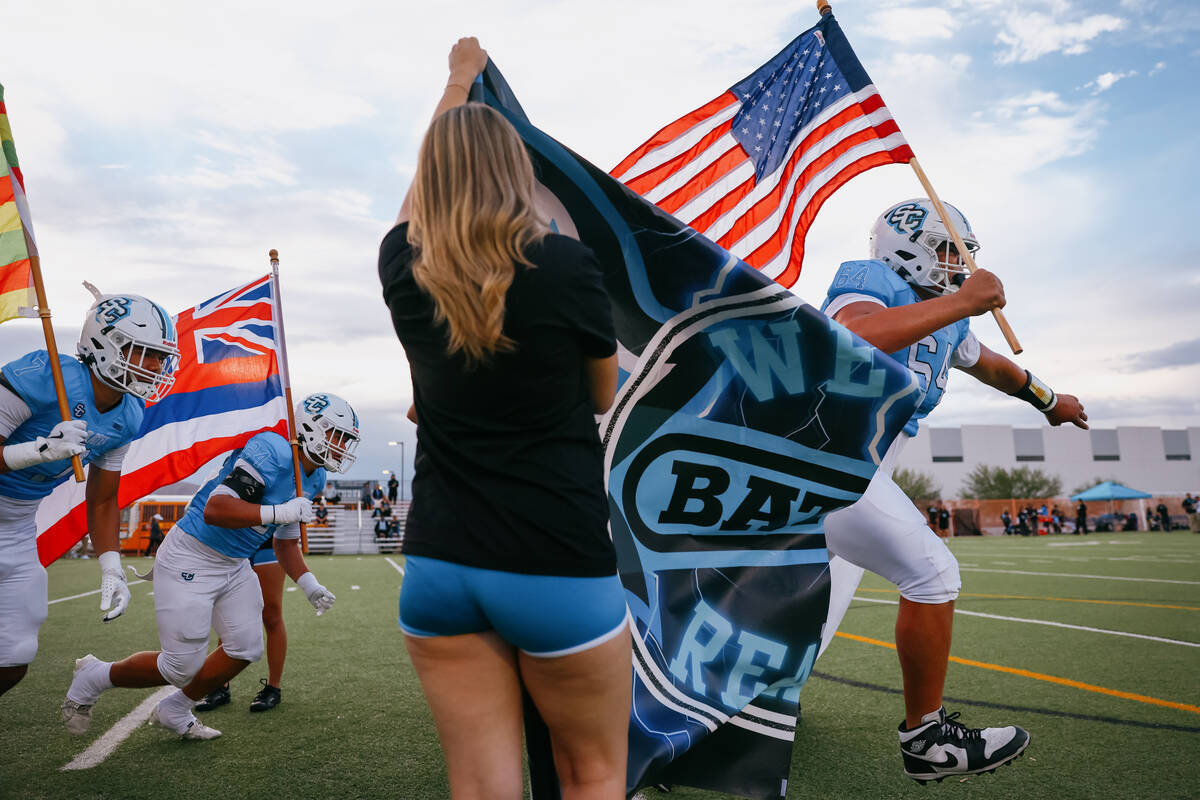 Dylan Bergquist crashes through Sloan Canyon’s banner, ready to kick off the game agains ...