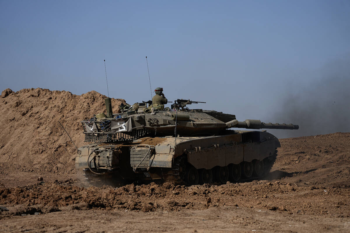 An Israeli soldier works on a tank at a staging area near the border with Gaza Strip, in southe ...