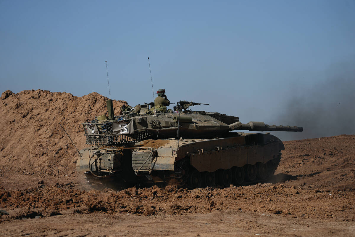 An Israeli soldier works on a tank at a staging area near the border with Gaza Strip, in southe ...