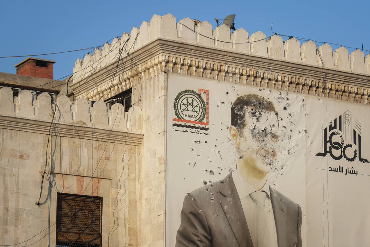 An image of Syrian President Bashar Assad, riddled with bullets, is seen on the facade of the p ...