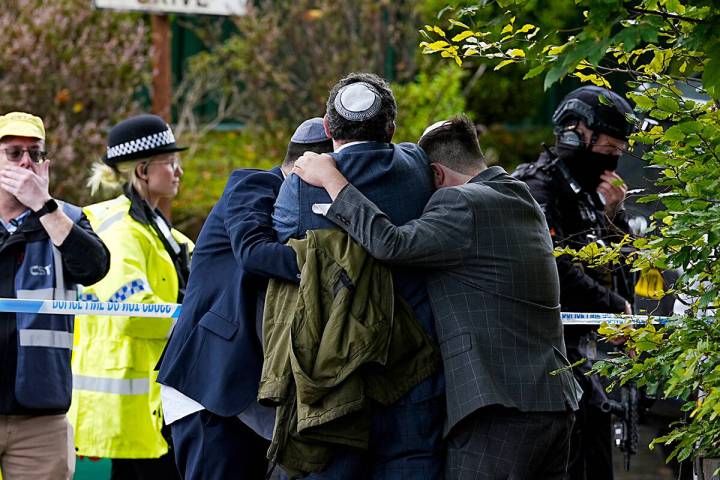 Members of the Jewish community comfort each other near to the Heaton Park Hebrew Congregation ...