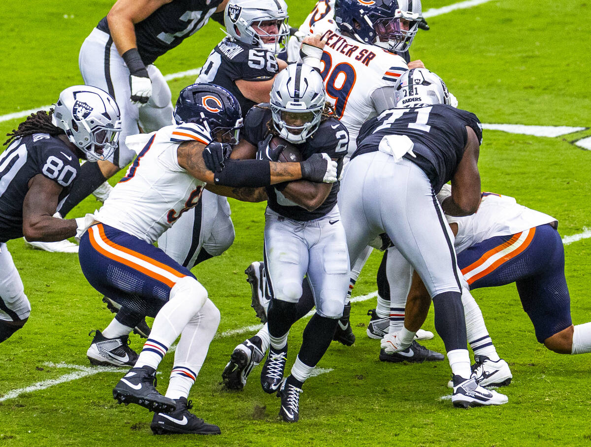 Raiders running back Ashton Jeanty (2) blasts through the line pursued pursued by Chicago Bears ...