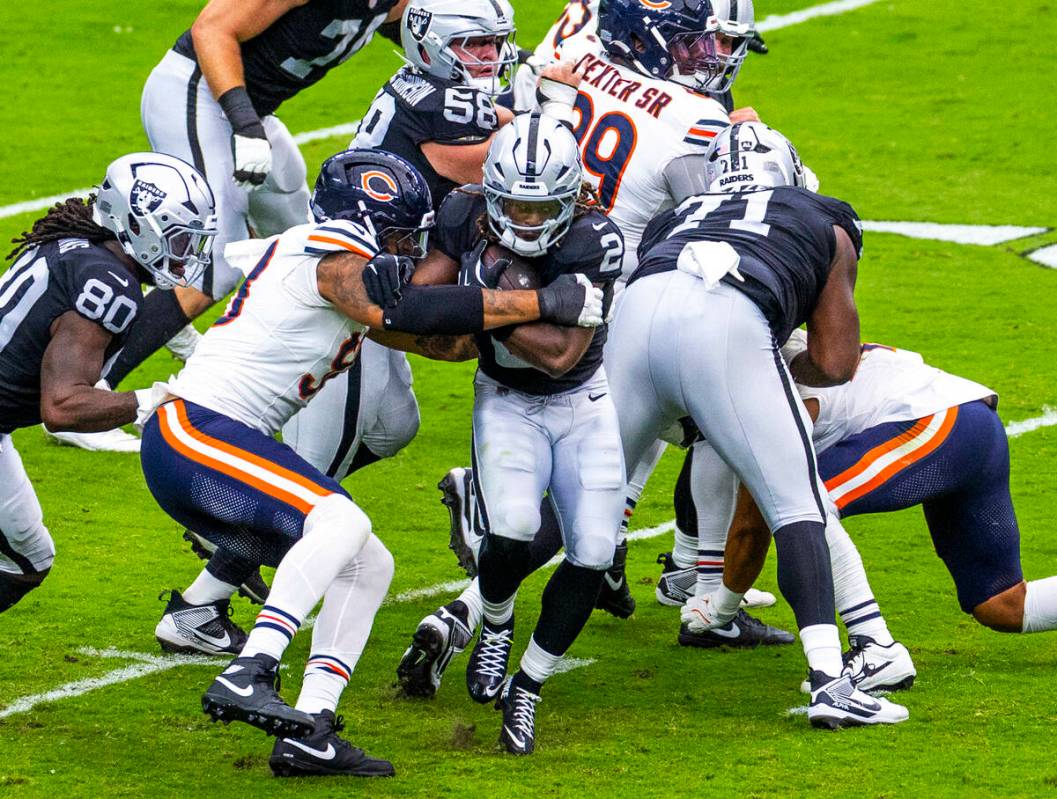 Raiders running back Ashton Jeanty (2) blasts through the line pursued pursued by Chicago Bears ...
