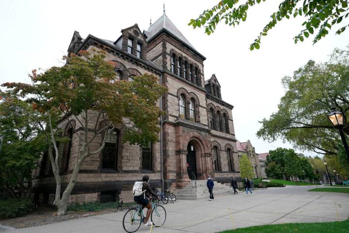 FILE - Passers-by walk and ride along a path on the campus of Brown University, in Providence, ...