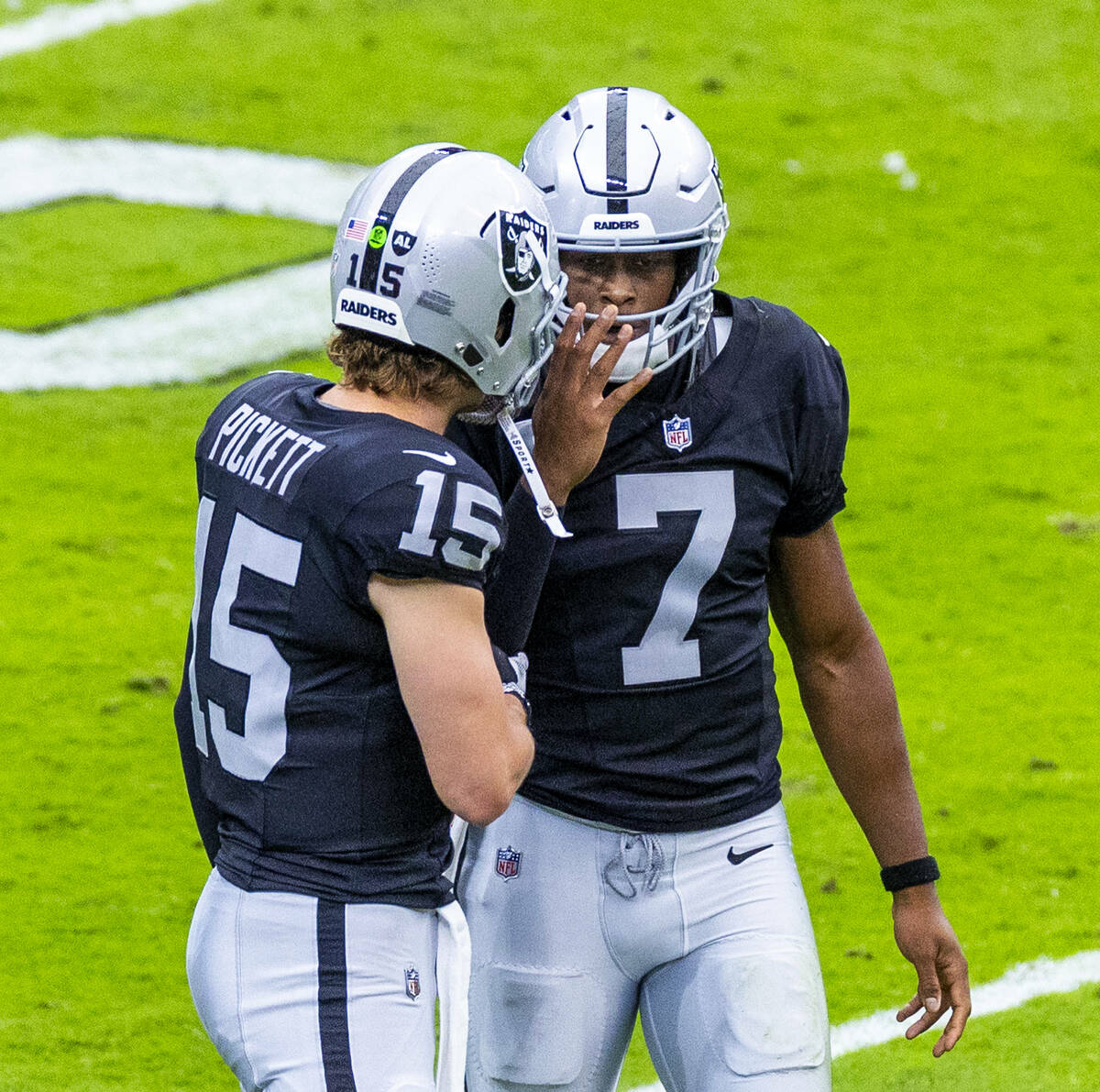 Raiders quarterback Geno Smith (7) talks with quarterback Kenny Pickett (15) after another inte ...