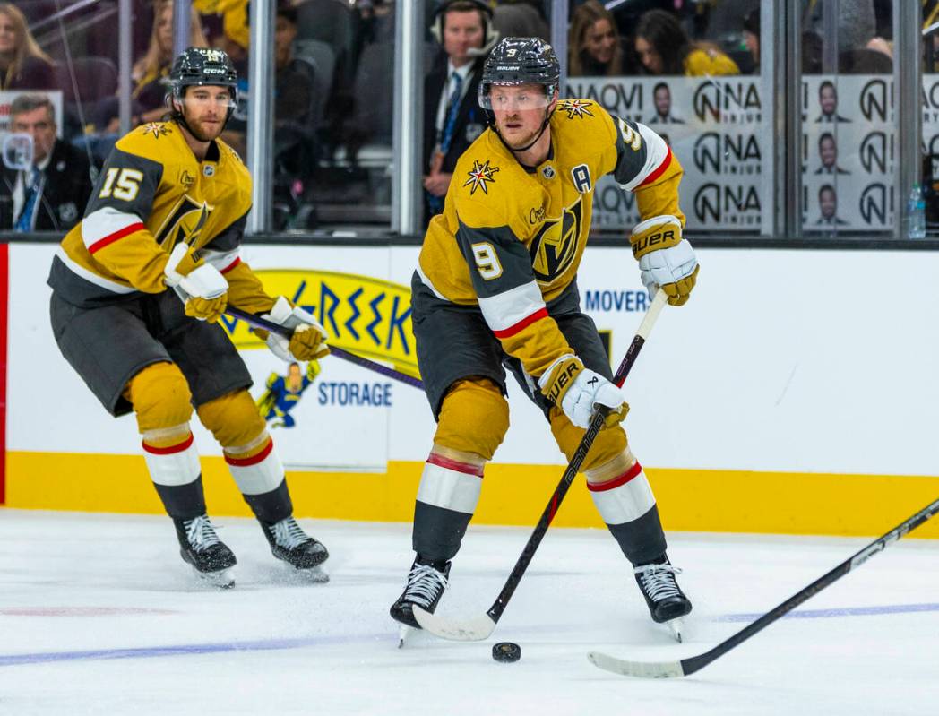 Golden Knights center Jack Eichel (9) looks to pass with defenseman Noah Hanifin (15) trailing ...