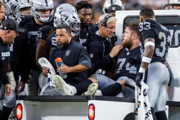 Raiders head coach Pete Carroll consoles offensive tackle Kolton Miller (74) as he is assisted ...
