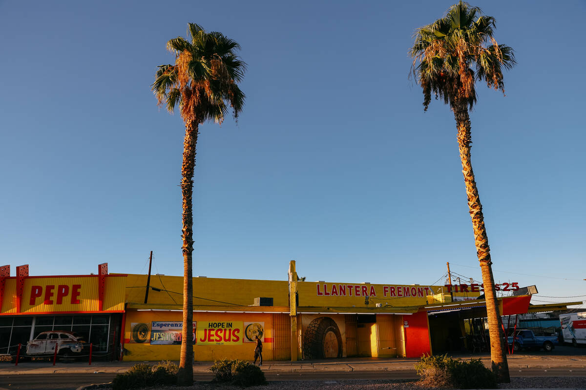 A pedestrian walks along an unshaded part of the sidewalk as palm trees line the median of the ...