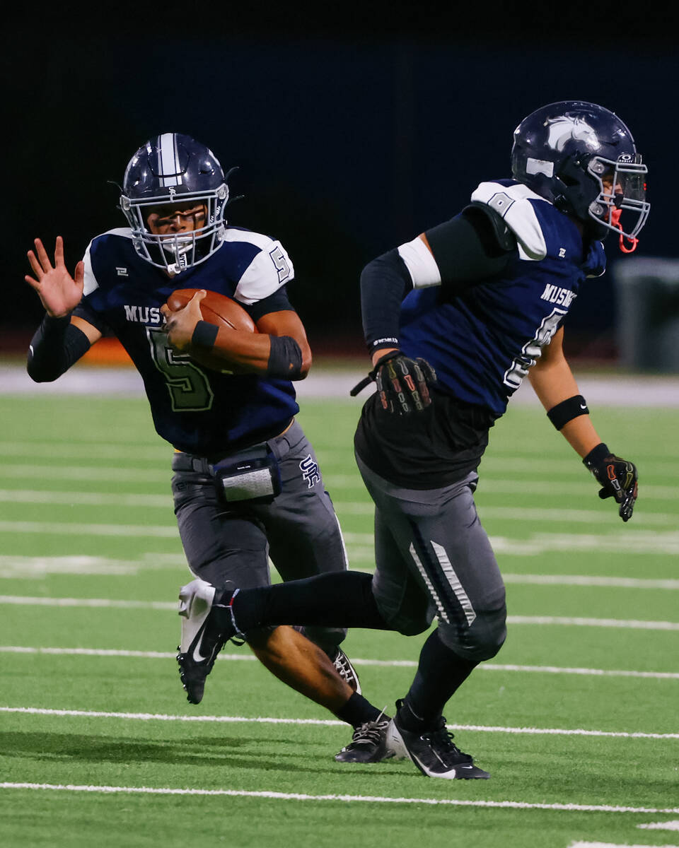 Shadow Ridge’s Isaiah Ruiz (5) runs one way with the ball as Colton Richter (8) runs the ...