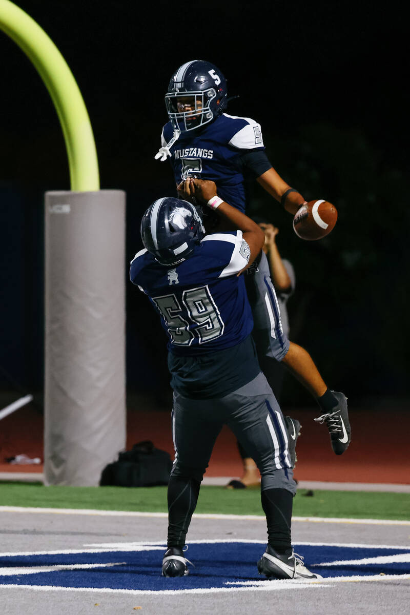 Shadow Ridge’s Alex London (59) lifts up teammate Isaiah Ruiz (5) after Ruiz ran in a to ...
