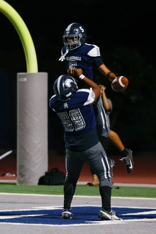 Shadow Ridge’s Alex London (59) lifts up teammate Isaiah Ruiz (5) after Ruiz ran in a to ...