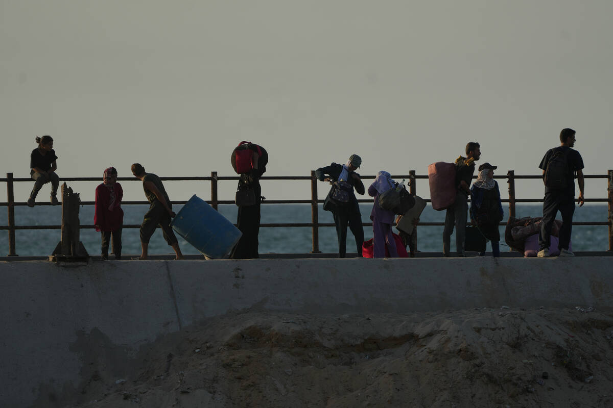 Displaced Palestinians flee northern Gaza carrying their belongings along the coastal road near ...