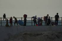 Displaced Palestinians flee northern Gaza carrying their belongings along the coastal road near ...