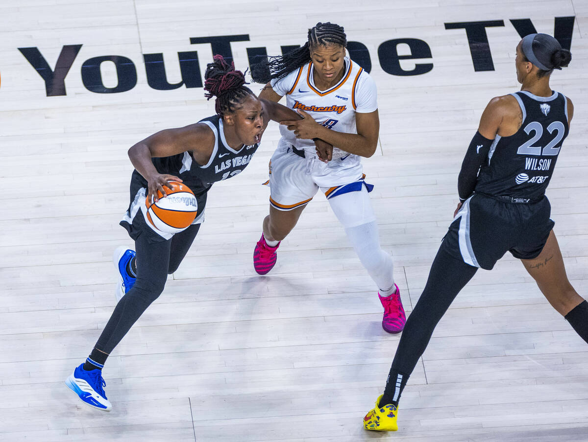 Aces guard Chelsea Gray (12) has her arm held by Phoenix Mercury guard Monique Akoa Makani (8) ...
