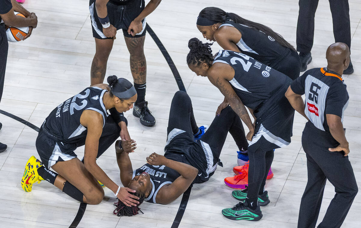 Aces guard Chelsea Gray (12) is comforted vey center A'ja Wilson (22) with teammates after ...
