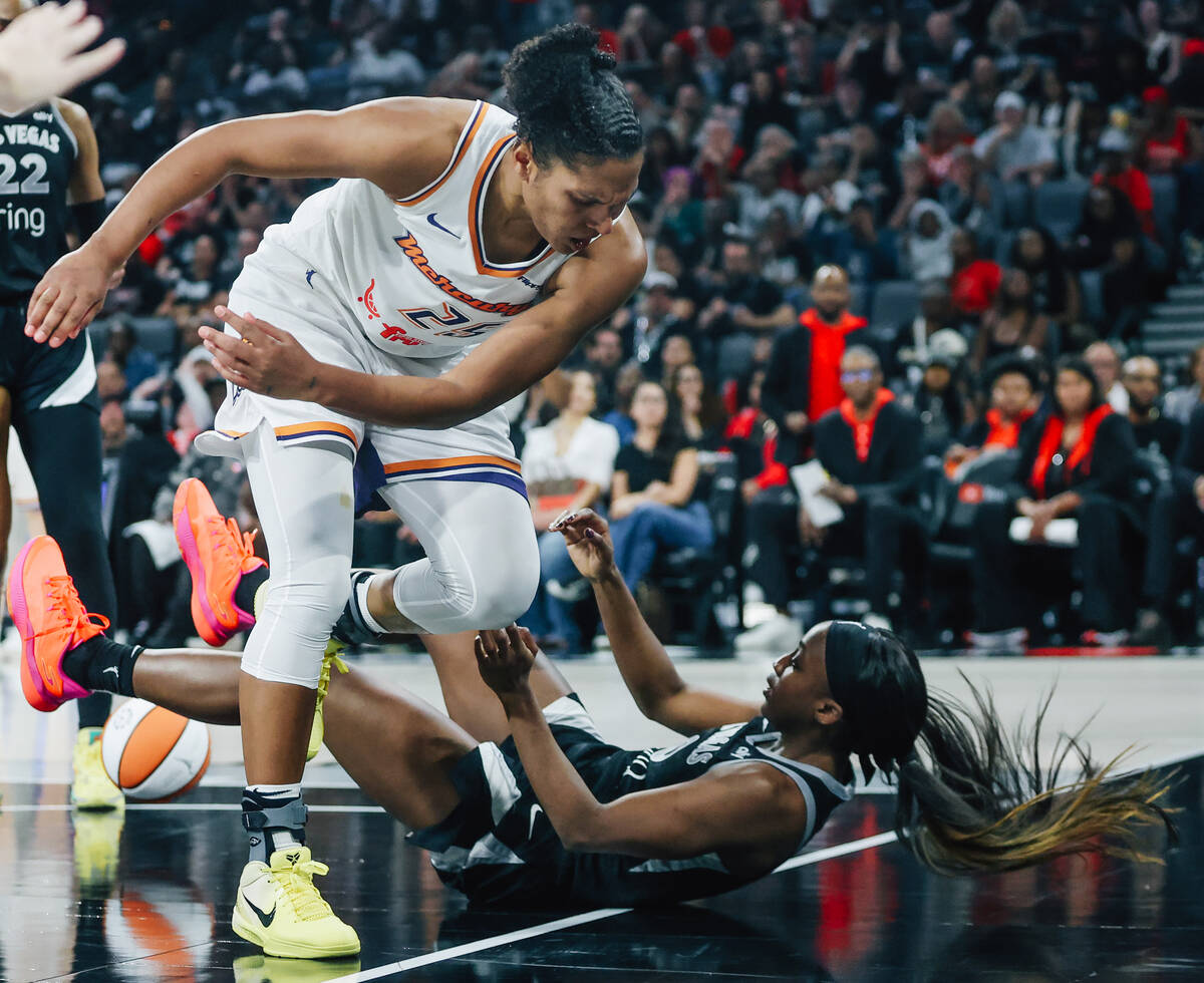 Aces guard Jackie Young (0) falls as Phoenix Mercury forward Alyssa Thomas (25) nearly trips ov ...