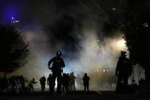 Law enforcement officers stand after deploying tear gas outside a U.S. Immigration and Customs ...