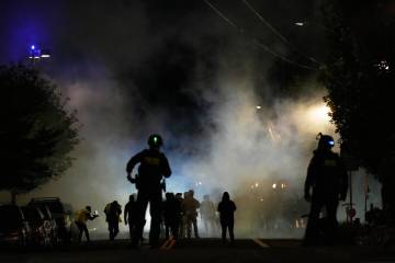 Law enforcement officers stand after deploying tear gas outside a U.S. Immigration and Customs ...