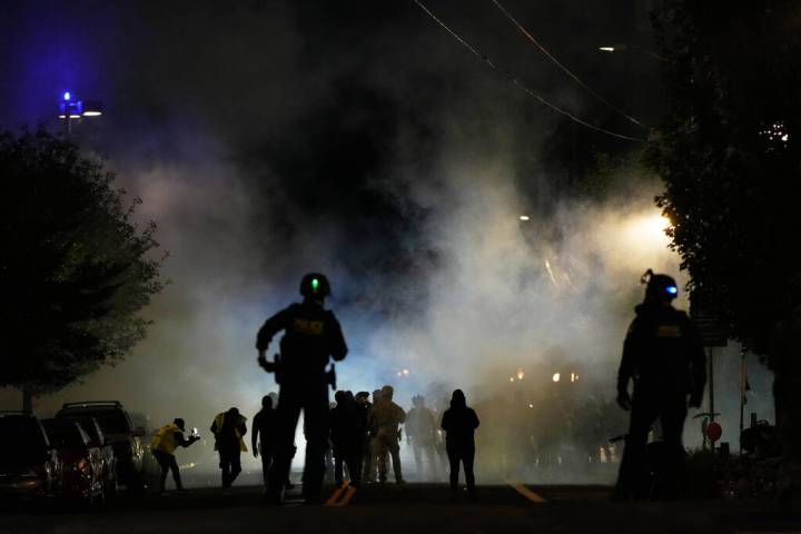 Law enforcement officers stand after deploying tear gas outside a U.S. Immigration and Customs ...