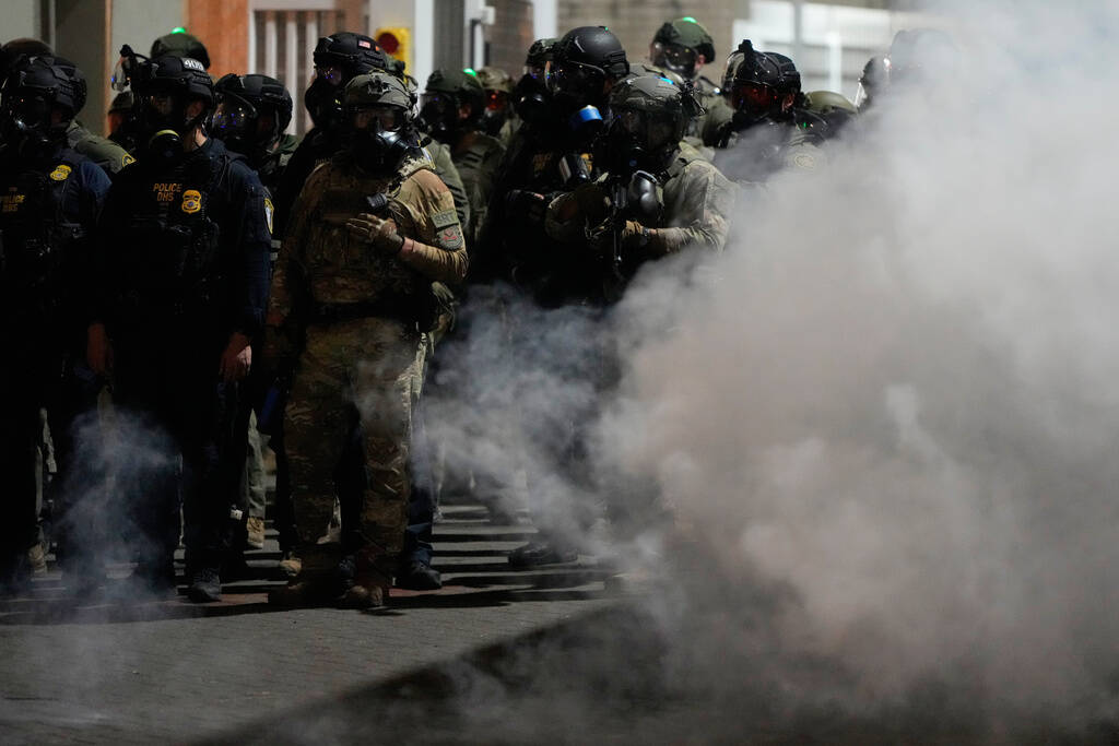 Law enforcement officers stand in tear gas outside a U.S. Immigration and Customs Enforcement f ...