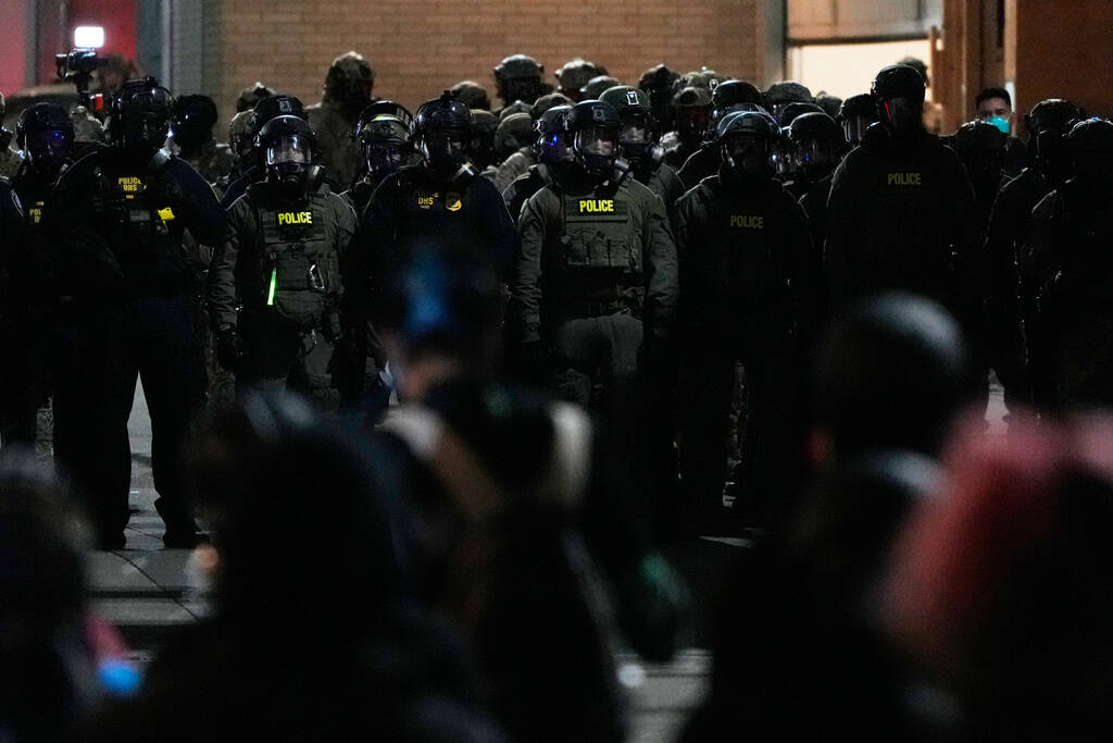 Law enforcement officers standoff against demonstrators outside a U.S. Immigration and Customs ...