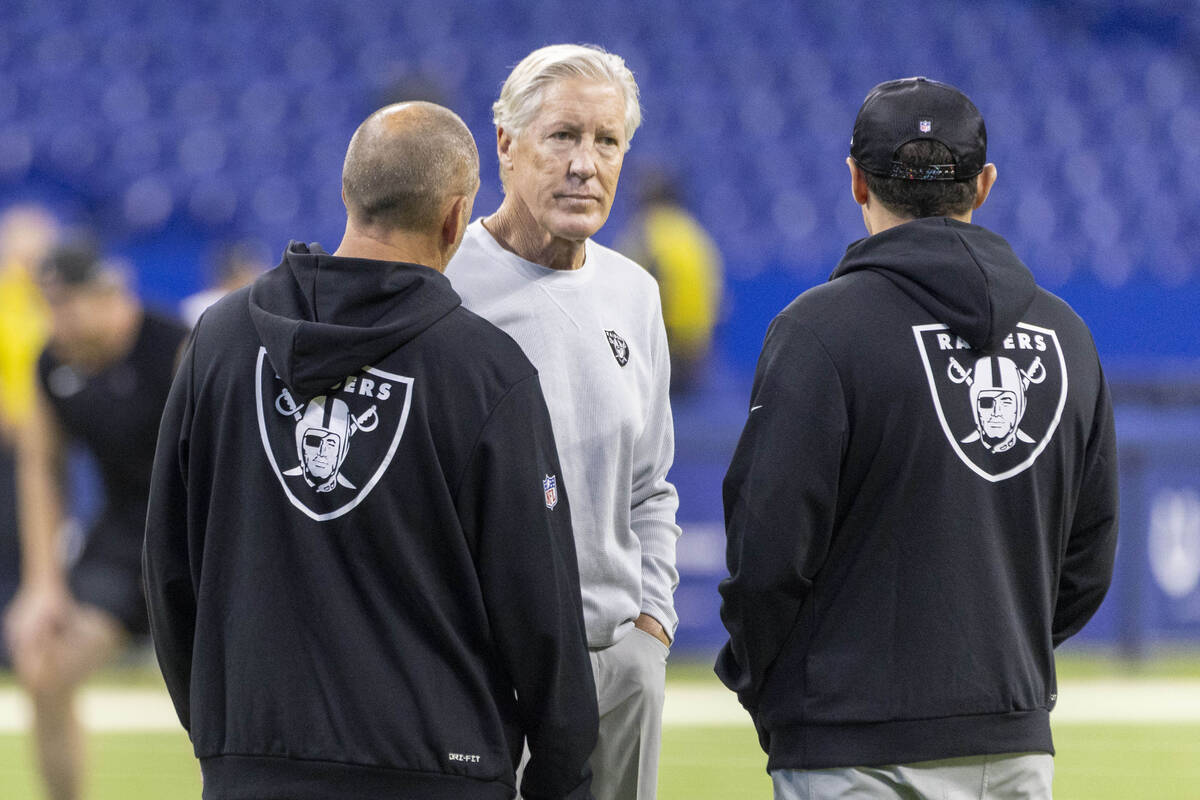 Raiders head coach Pete Carroll meets with assistant coaches on the field before an NFL game ag ...